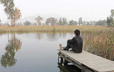 Image showing man sitting on a wooden pier