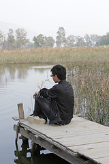 Image showing man sitting on a wooden pier