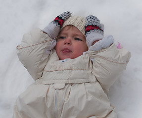 Image showing Little girl lays on the snow