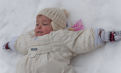 Image showing Little girl lays on the snow