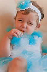 Image showing Little girl in the blue dress eats cookie