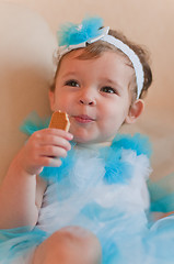 Image showing Little girl in the blue dress eats cookie