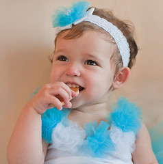 Image showing Little girl in the blue dress eats cookie