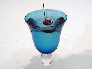 Image showing Freshly dropped cherry in blue glass