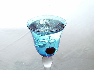 Image showing Freshly dropped cherry in blue glass
