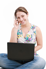 Image showing beautiful young woman talking over the phone and using laptop 