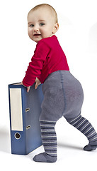 Image showing small child standing next to blue ring binder