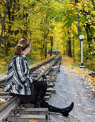 Image showing Young women sits on a rails