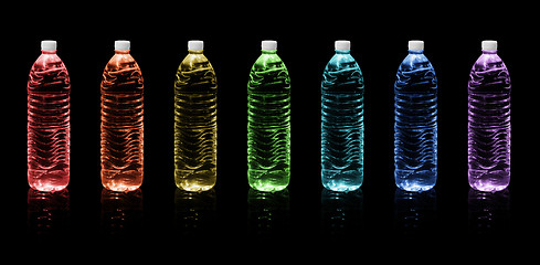 Image showing Bottles of drinking water. Rainbow colors on a black