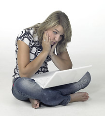 Image showing bored girl sitting on the floor with white laptop