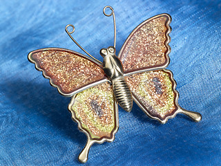 Image showing butterfly trinket on blue fabrics