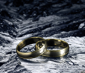 Image showing two golden wedding rings on ice surface