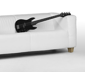 Image showing black bass guitar on white couch