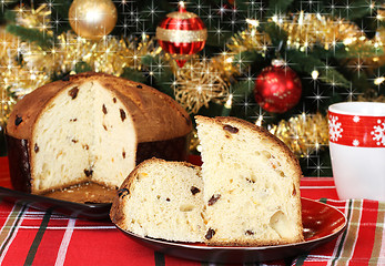 Image showing Panettone, whole and sliced, in front of a festive Christmas tre