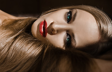 Image showing of attractive girl with long blonde hair and red lips  which lies and looks into the camera