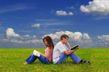 Image showing two teenagers studying outdoors on grass