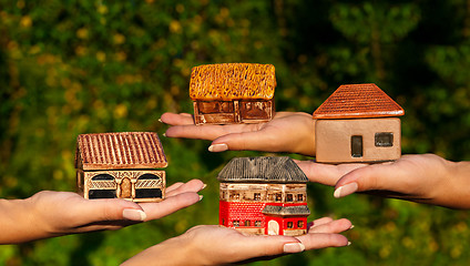 Image showing Four different houses in human hands