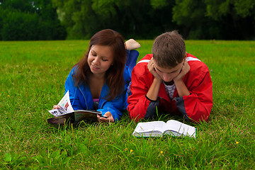 Image showing two teenagers studying outdoors on grass