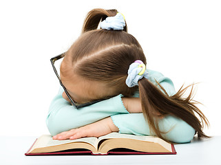 Image showing Little girl is sleeping on a book