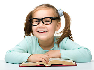Image showing Little girl reads a book while wearing glasses