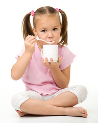 Image showing Cute little girl is eating yogurt