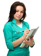 Image showing Young attractive woman doctor is writing