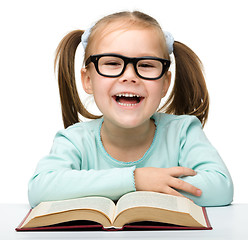 Image showing Little girl reads a book while wearing glasses