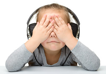Image showing Unhappy girl listening music using headphones