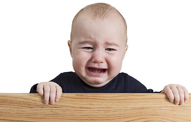 Image showing crying young child holding wooden board