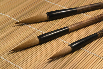 Image showing chinese brushes on wooden mat detail