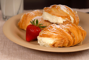 Image showing Three sfogliatelle's with strawberry on tan plate