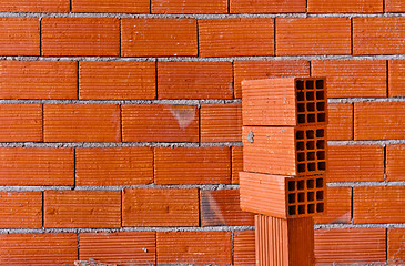 Image showing Brick wall with a stack of new bricks