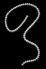 Image showing White pearls on the black silk as background 
