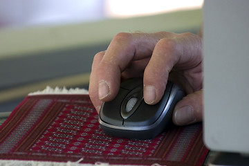 Image showing Hand over a Wireless Mouse on a Rug