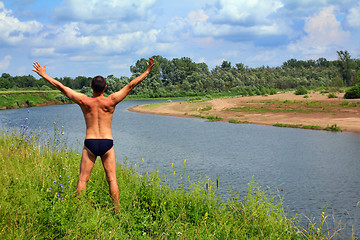 Image showing man with hands up near river