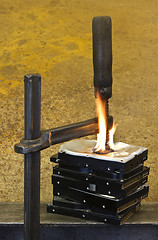 Image showing clamp pressing on burning stack of hard drives