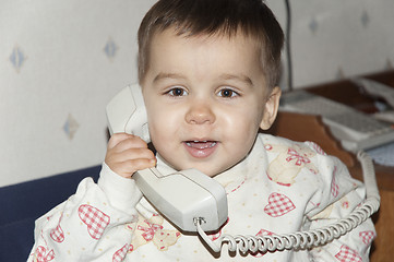 Image showing Cute little baby is talking on  phone