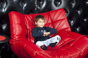 Image showing Kid on a red leather sofa