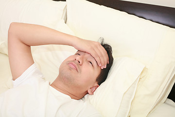 Image showing Close up of young man lying down in bed taking temperature and having flu