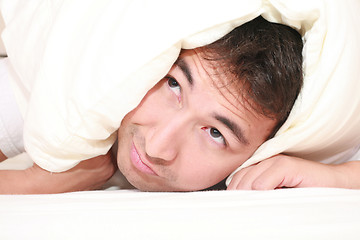 Image showing Man trying to sleep with a pillow over his head and close to wake up time