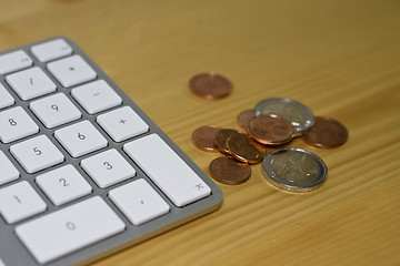 Image showing Keyboard and euro coins on wooden desk