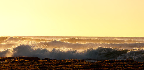 Image showing Setting sun lights crashing waves