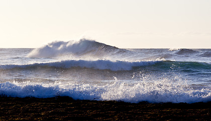 Image showing Setting sun lights crashing waves