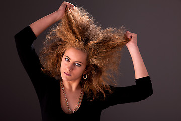 Image showing Beautiful woman  with hands holding the hair, looking to camera, studio shot