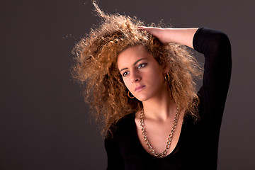 Image showing Beautiful woman  with hands holding the hair, looking to camera, studio shot