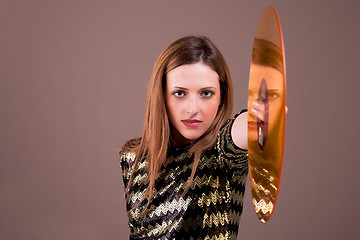 Image showing beautiful blonde woman standing holding a golden vinyl disc