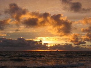 Image showing A sunset over the sea with a lighthouse in the horizon