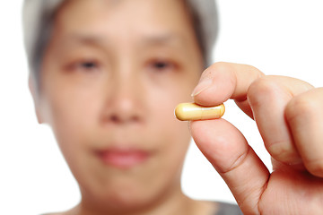 Image showing mature woman holding pill