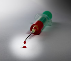 Image showing syringe laying on table filled with blood