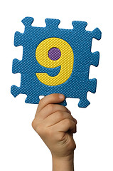 Image showing Children hand holding the number Nine. White isolated number